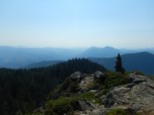 view of mountains and forest with tall rock cairn a lower right