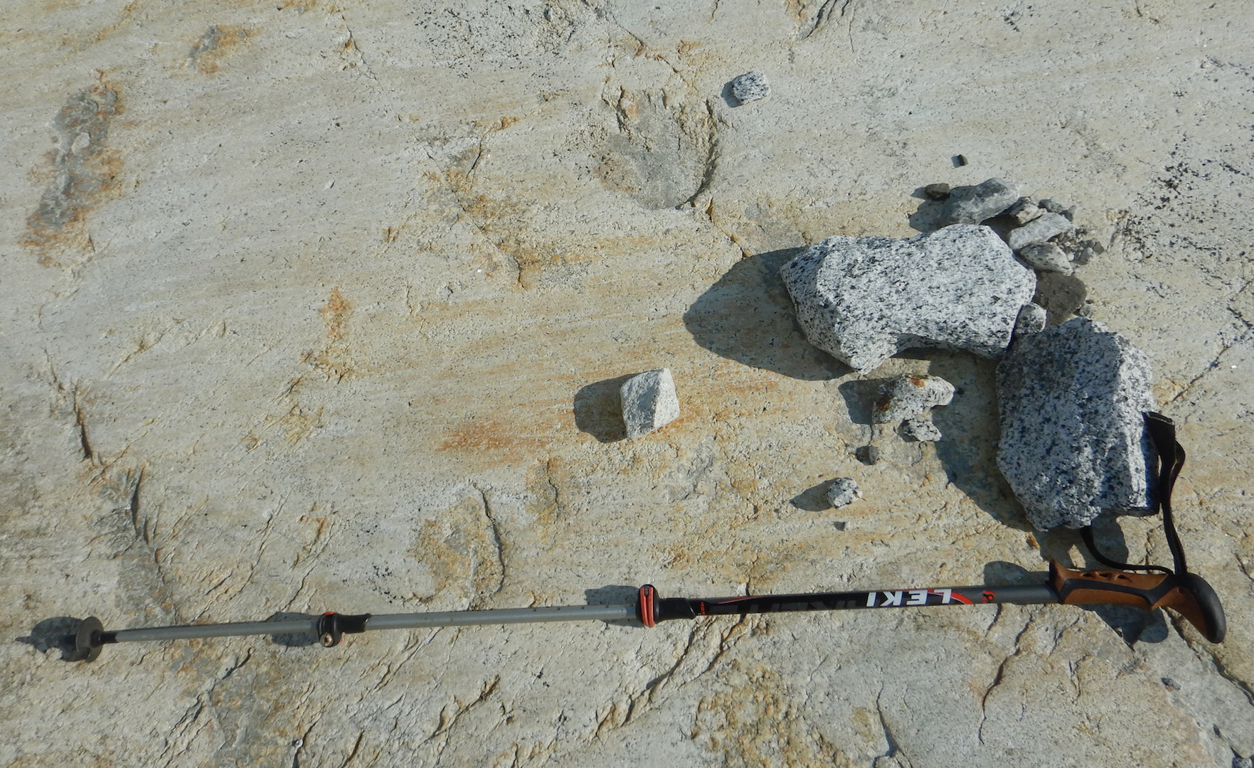hiking pole lying on bare rock. Rock shows faint horizontal striations.